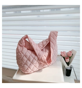 Detail of pink quilted dumpling bag beside tulips with soft natural lighting