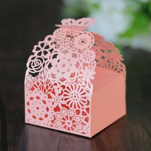 Pink laser-cut wedding favor box with hollow butterfly and floral patterns on wood