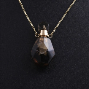 Close-up of flame-shaped aventurine crystal perfume bottle pendant with gold chain