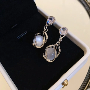 Détail de boucles d'oreilles argentées avec pierres œil de chat sur velours noir