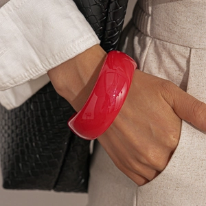 Chic red resin bangle styled with beige linen trousers and a premium black crocodile bag