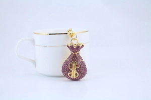 Close-up of golden money bag keychain with purple crystals and dollar sign detail