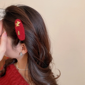 Detail of red plush hair clip with gold metal animal and snowflake earring on model