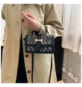 Detail of leopard print handbag featuring black leather trim and gold H-buckle closure