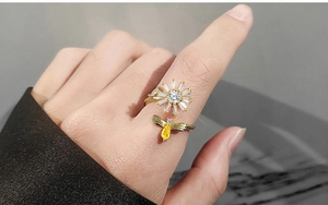 Detail of spinning sunflower and bee ring with sparkling zircon stones on model's finger