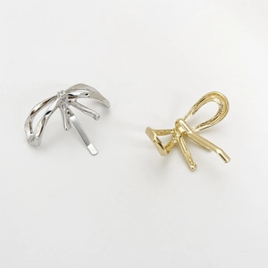 Detail showing sleek gold and silver metallic bow clips for elegant low ponytails