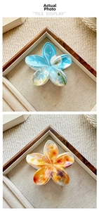 Detail view of tropical flower hair claws in blue dandelion and orange floral patterns