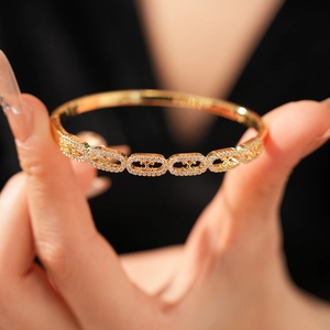 Detailed view of a gold-plated Triomphe bracelet with cubic zirconia paving on links