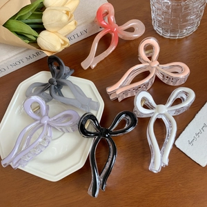 Elegant large bow hair clips in six colors on a wooden table with floral accents