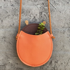 Detail of lychee textured leather mini crossbody bag with orange and brown patchwork