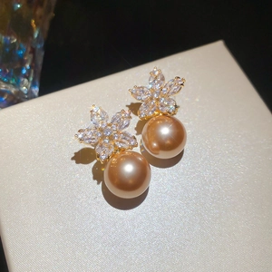 Detailed view of silver flower earrings with white zircons and champagne pearls on leather