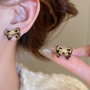 Close-up of tortoise shell bow earrings with gold plating and cubic zirconia inlay