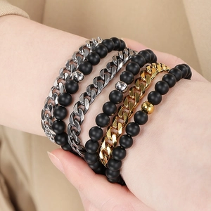 Detail of men's layered Cuban chain and black agate bead bracelets on a male wrist