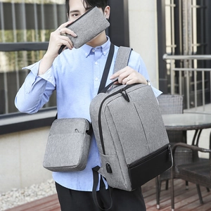 Three-piece men's grey oxford backpack set with USB port shown on a male model outdoors