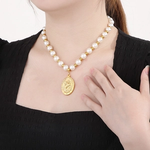 Collier médaille Saint Christophe avec perles blanches et dorées porté par un mannequin