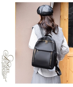 Rear view of a model wearing the black nylon backpack with elegant golden zippers