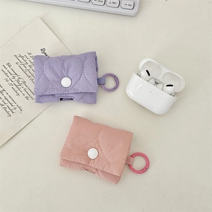 Dettaglio della custodia AirPods in tessuto trapuntato a cuore con chiusura a scatto