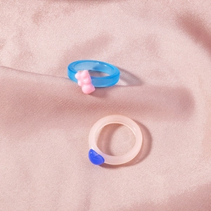 Detail of gummy bear and heart resin rings on pink satin fabric background