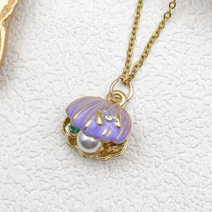 Detail of purple enamel shell pendant with a white pearl and gemstones on a gold chain