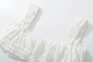 Détail du haut caraco blanc avec texture de tissu plissé et bordure en dentelle délicate