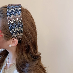 Gros plan d'un bandeau tressé large aux motifs géométriques bleus et marron sur modèle