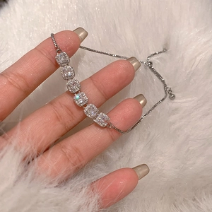 Détail d'un bracelet réglable argenté avec six zircons carrés sur un fond en peluche douce