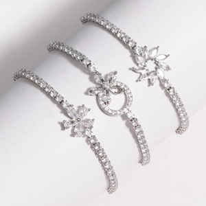 Détail de trois bracelets fleurs argentés avec zircons brillants sur un support cylindrique
