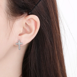 Detailed close-up of a silver stainless steel cross earring with sparkling rhinestones