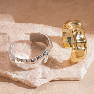 Close-up of gold and silver chunky cuff bracelets with textured molten lava metal finish