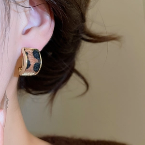 Close-up of leopard print C-shaped hoop earrings featuring gold edges worn by a model