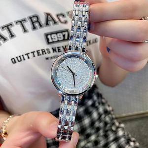 Close-up of a silver metal watch with a full diamond-encrusted dial on a model's wrist