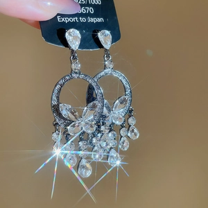 Detailed macro of dark gunmetal silver needle earrings with butterfly tassels and crystals