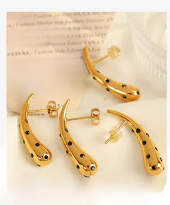 Macro shot of gold teardrop earrings featuring black crystal accents on silk fabric