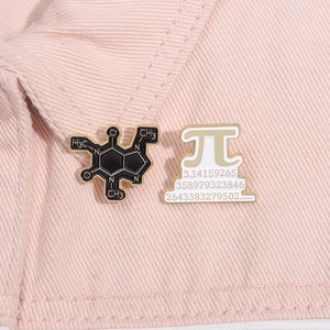 Detail showing caffeine molecule and Pi symbol enamel pins on pink denim fabric
