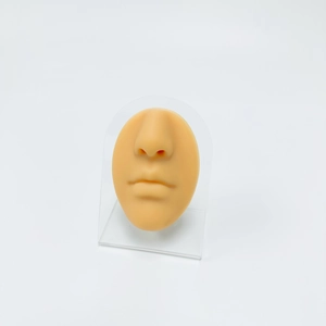 Realistic skin-tone silicone nose and mouth model on acrylic stand for piercing practice