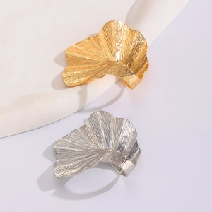 Detailed close-up of metallic ginkgo leaf jewelry in gold and silver finishes
