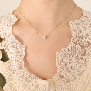 Minimalist gold necklace featuring a brilliant round-cut zircon pendant on model
