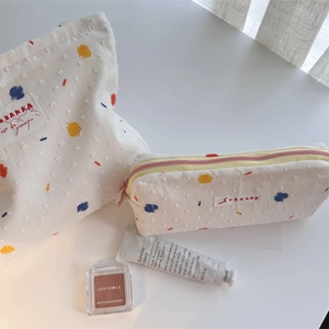 White canvas organizer pouch set with colorful prints and woven brand labels