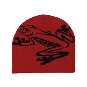 Detail of red knit beanie featuring black frog jacquard pattern and soft texture