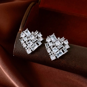 Detailed view of silver heart earrings with sparkling cubic zirconia on brown leather
