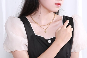 Gros plan d'un collier doré à deux rangs en acier titane avec pendentif cœur