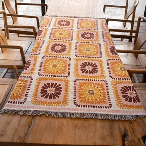Detailed close-up of Bohemian woven pattern with colorful tassels on a wooden table