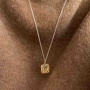 Vintage gold square coin necklace with number 5 pendant on beige knit background