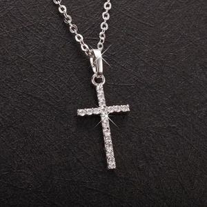Close-up of a silver cross pendant necklace with sparkling cubic zirconia on a dark surface