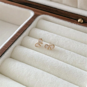 Macro detail of gold bow stud earrings with sparkling zircons in a jewelry display box