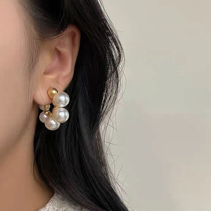 Close-up of elegant C-shaped pearl hoop earrings with gold metal and zircon accents