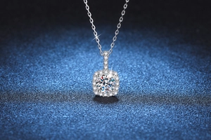 Detailed close-up of a 1-carat moissanite pendant with halo diamonds on a blue background