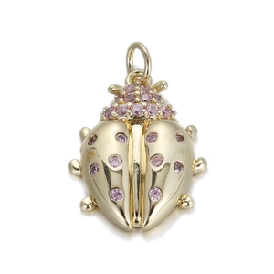 Detailed close-up of a beetle pendant in gold metal with pink gemstone inlays