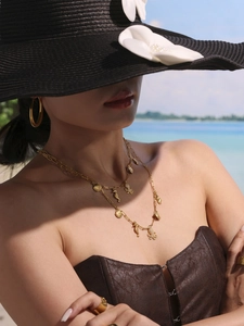 Golden ocean jewelry set with shell and octopus pendants worn on a sunny beach