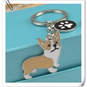 Detailed view of metal Corgi keychain with a brown and white dog charm and a black paw tag